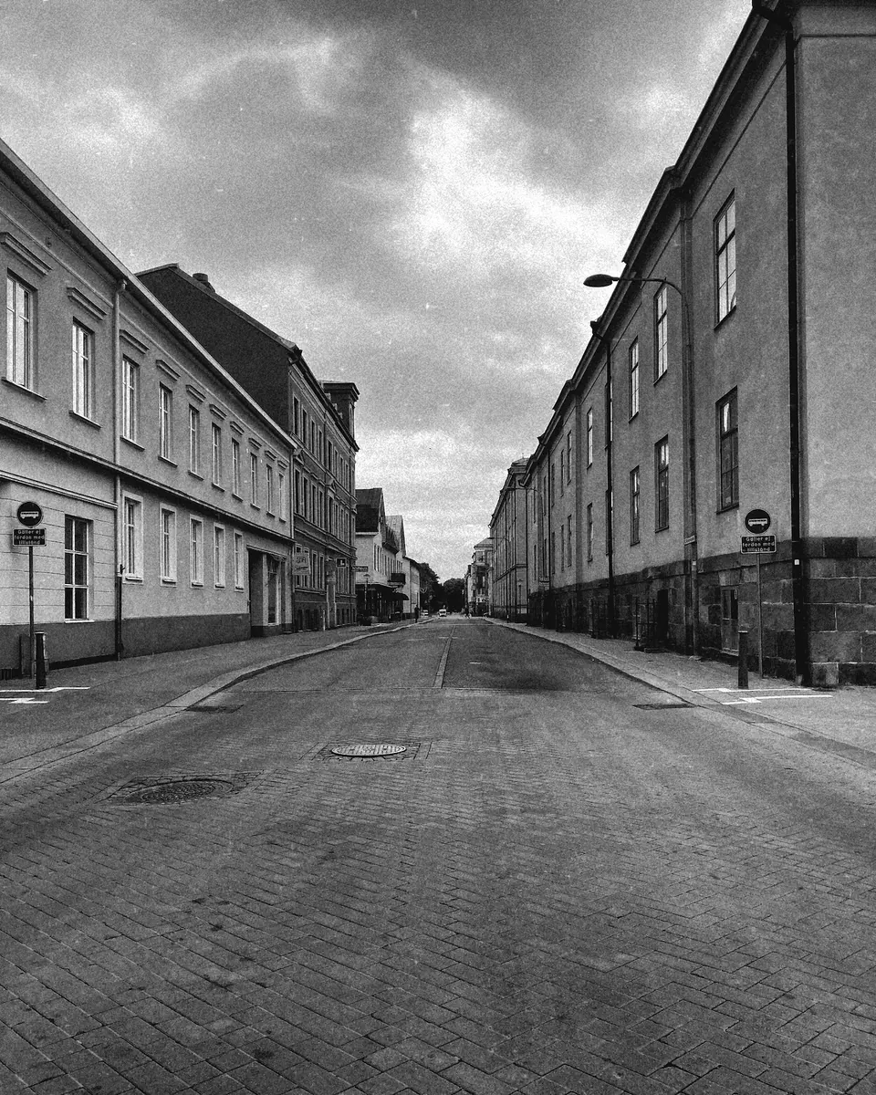 Tom kullerstensgata mellan gamla stenhus under tung himmel, Kristianstad